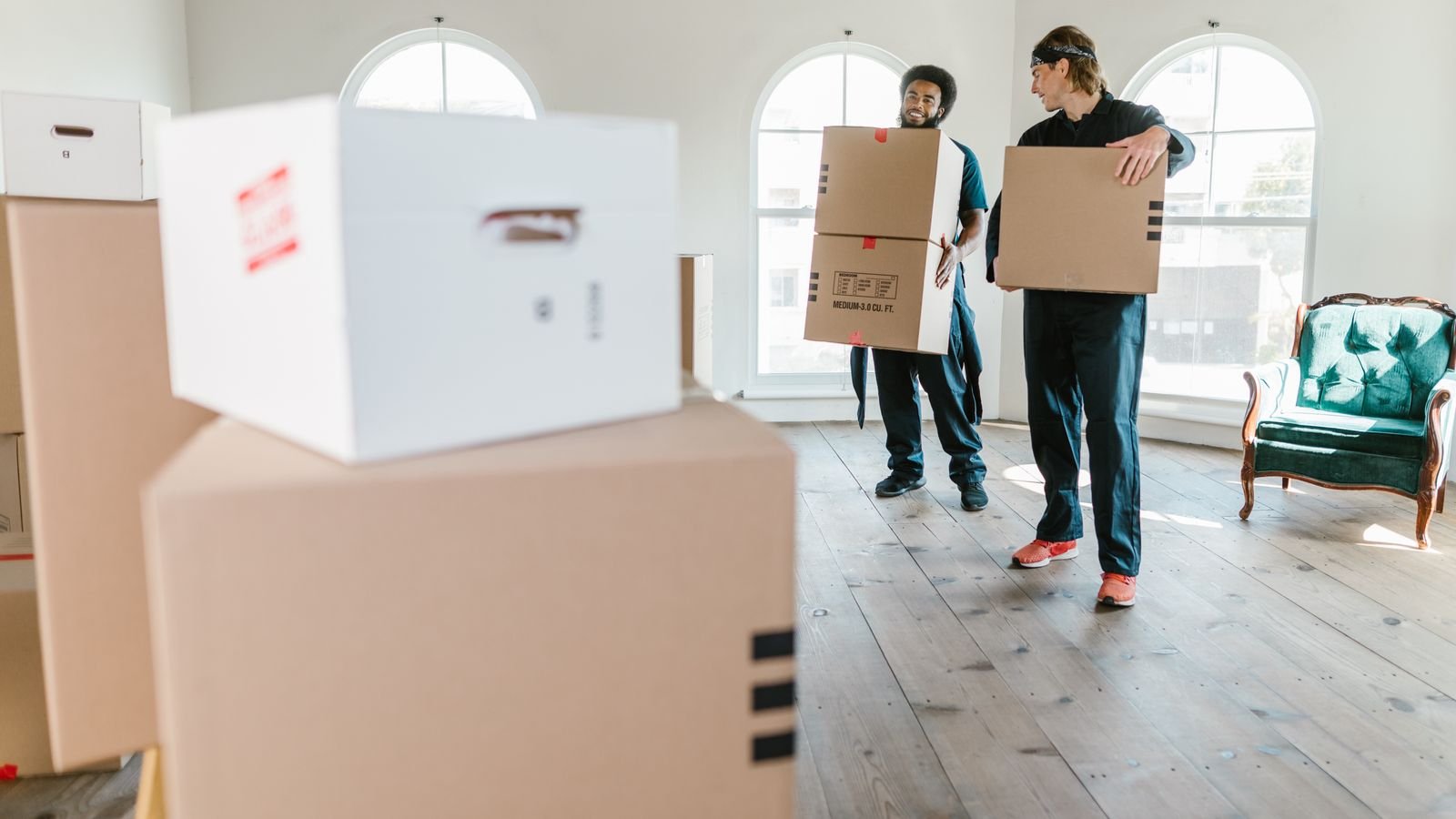 Zwei Mitarbeiter einer seriösen Entrümpelungsfirma tragen Kartons aus einer Wohnung